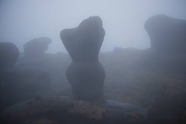 Harsh geological structure on the top of Jacob's Ladder trail in the Peak District. Misty weather adds a serene background with other rocks and geological formations visible in the background.