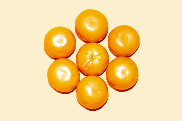 A visually appealing composition featuring fresh tangerines arranged in abstract floral patterns on a monochrome orange background. The warm tones and creative placement highlight the textures and natural beauty of the citrus fruit. This image is ideal for themes related to healthy eating, organic food, fresh produce, artistic food styling, and vibrant color palettes. The symmetrical yet playful arrangement makes it suitable for food blogs, wellness branding, nutrition marketing, and creative design projects.