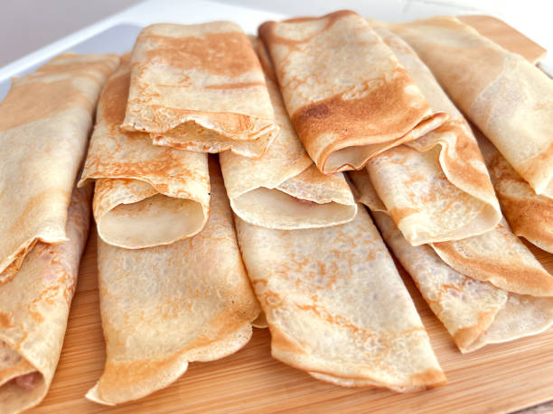 istock Folded and stuffed pancakes lie on a wooden board in the kitchen 2204176706