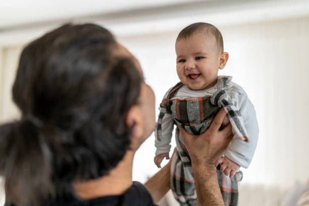 istock Father lifting baby smiling indoor. 2204177935
