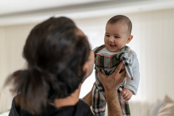 istock Father lifting baby smiling indoor. 2204177968