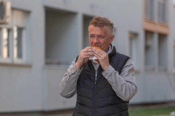 istock Man eating burger outdoors in the city 2204183553