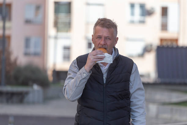 istock Man eating burger outdoors in the city 2204183861