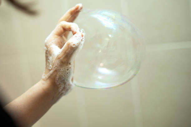 child's hand submerged in foam, playfully creating a soap bubble from a circle formed by fingers. A joyful moment capturing innocence and creativity