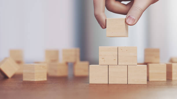 istock Manually Building a Pyramid from Wooden Blocks 2204190620