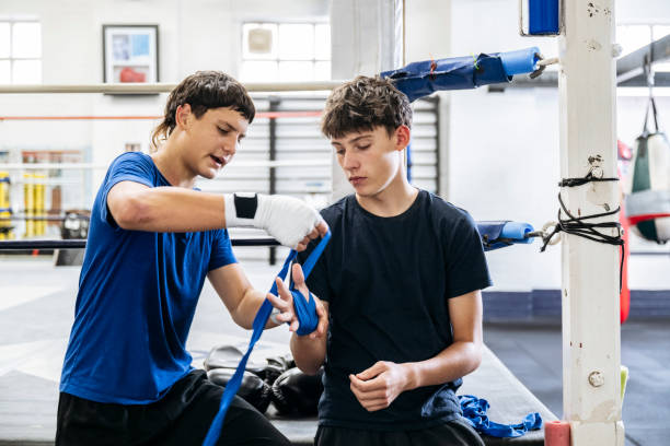 istock Young boxers helping each other wrap hands 2204191257