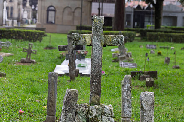 istock Old stone cross standing in cemetery with green grass 2204191674