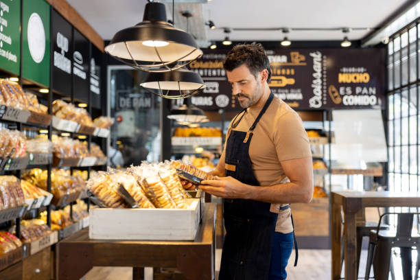 istock Business owner working at a bakery and restocking the shelves 2204192532