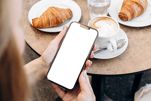 istock Mockup woman's hand holding using smart phone with white blank screen POV at cafe on breakfast table, mobile app design and advertising, online marketing 2204197030