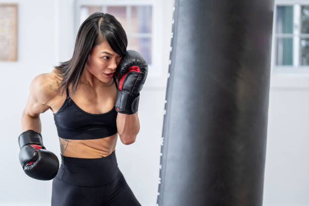istock Strong Female Muay Thai Boxer Targeting a Heavy Bag 2204197221