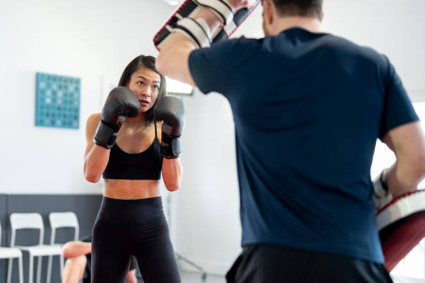 istock Focused Female Fighter Locking Eyes with Muay Thai Trainer 2204197225