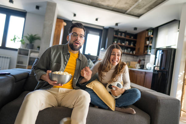 istock Couple cheering while watching soccer match on tv at home 2204198155