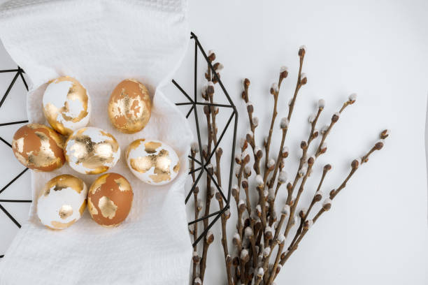 istock Easter golden eggs with willow branches in a basket on a white background, top view. Easter festive banner. 2204203257