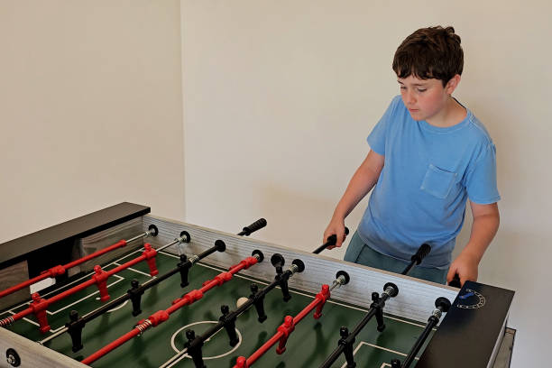 istock 12 year old boy playing foosball 2204204739