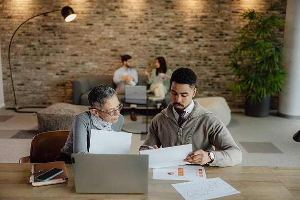 istock Business Colleagues Collaborating on Reports in Modern Office Environment 2204206250