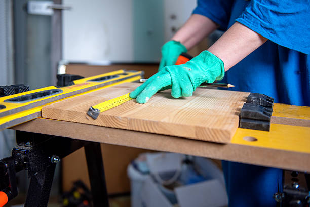 Person measuring wooden board with tape measure and pencil. stock photo