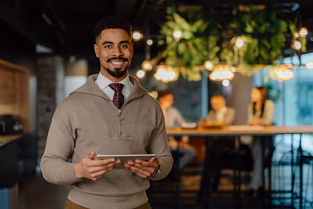 istock Confident Professional Holding Tablet in Modern Office Environment with Team Collaboration 2204211815