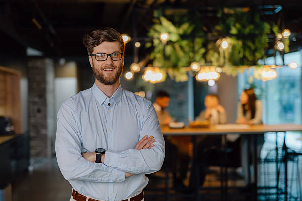 istock Professional Businessman Standing in Modern Office with Colleagues Working in Background 2204211824