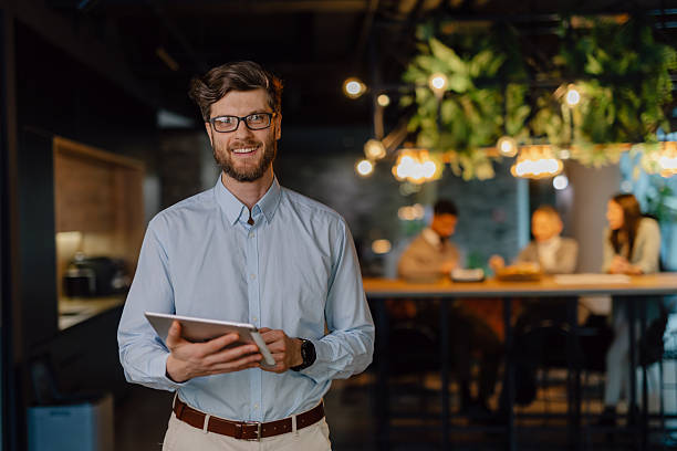 istock Smiling Businessman Holding Tablet During Team Collaboration in Modern Office 2204211834