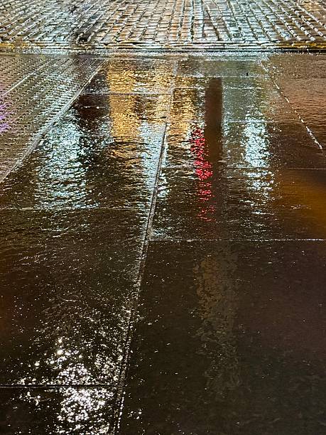 istock Rain-soaked pavement reflecting vibrant city lights at night 2204212018