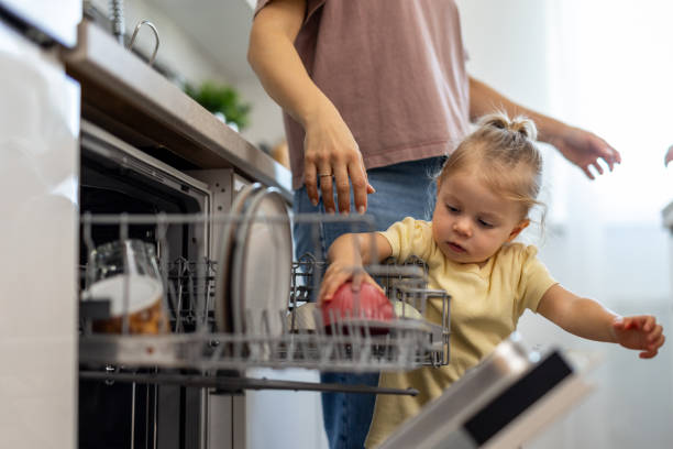 istock Curious toddler helping mother emptying dishwasher in kitchen 2204212233