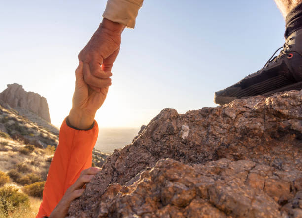 istock Hiker offers a helping hand in desert at sunset 2204216860