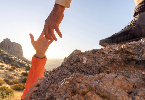istock Hiker offers a helping hand in desert at sunset 2204216866