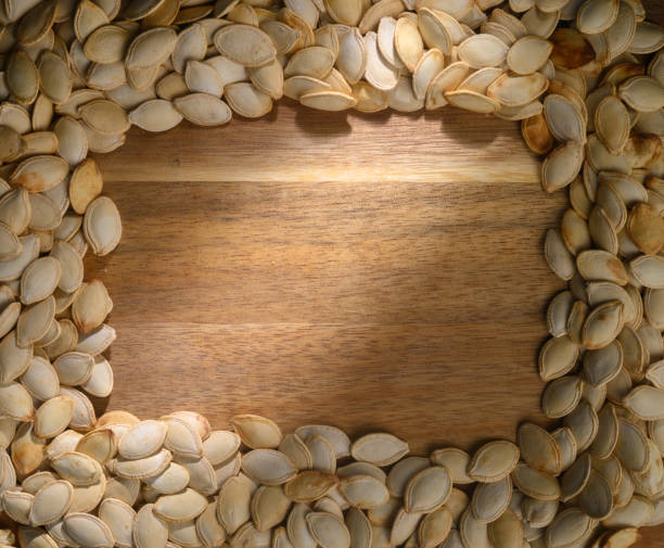 istock Pumpkin seeds arranged in a decorative border around a wooden surface inviting autumn creativity 2204218009