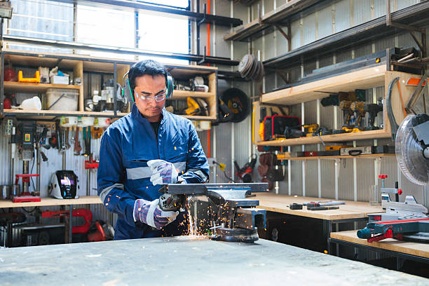 Latin worker using angle grinder in workshop creating sparks stock photo