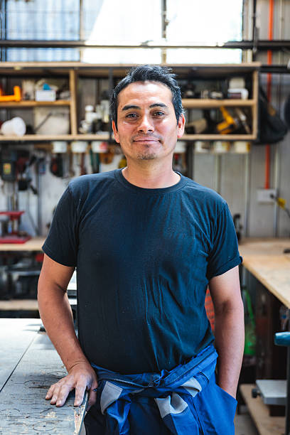 istock Portrait of latin carpenter smiling in his workshop with tools in background 2204223515