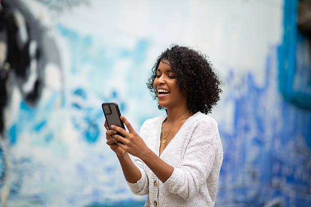 istock smiling young african american woman using mobile phone 2204226974