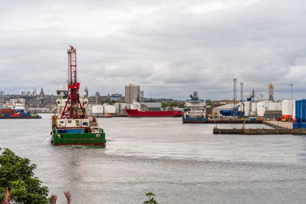 REM Arctic, an offshore supply ship, berthed in Aberdeen Harbour, Scotland. She is operated by REM offshore, which is headquartered in Norway. The photo includes logos of Asco, a marine services company, Peterson, an electrical logistics company and Caledonian Oil.