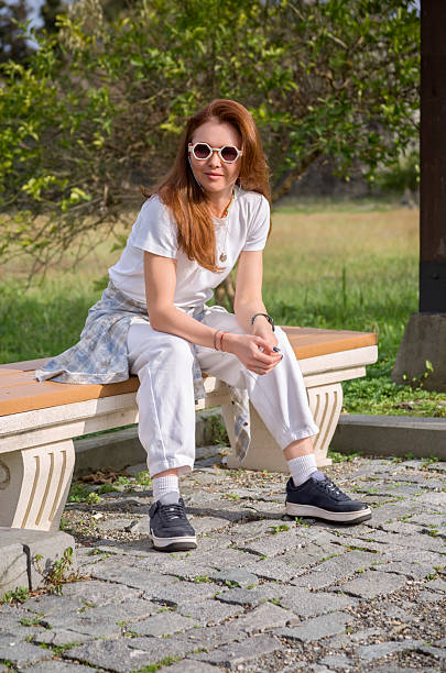 istock A beautiful woman in white clothes sits on a park bench 2204259019