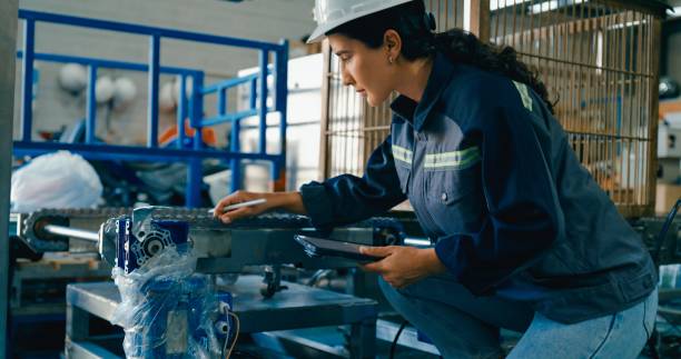 istock Young female technician in factory uses digital tablet and operates control panel to manage industrial equipment and ensure proper functioning. Robotic Industrial Factory. 2204259114
