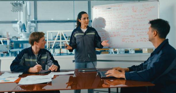 istock Group of engineers having meeting in factory, using whiteboard for discussing project details and planning. Robotic Industrial Factory. 2204259130