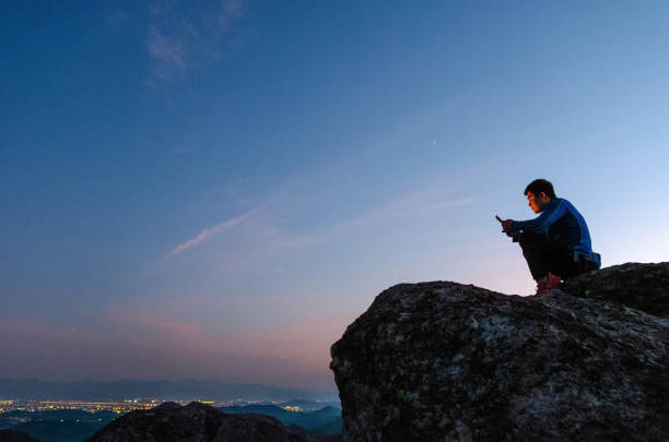 istock Watching your phone on the mountaintop at sunset 2204260586