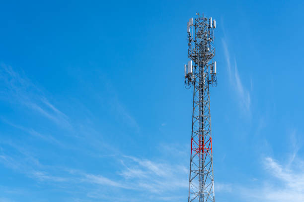 istock A tall telecommunications tower with antennas against a bright blue sky with wispy clouds. 2204262782