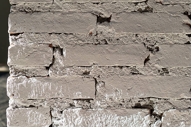 A close-up shot of a textured, white painted brick wall with thick mortar joints, showing a rustic architectural detail.