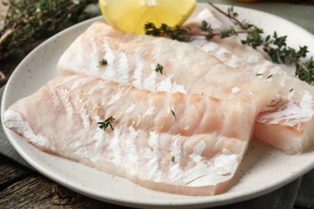 istock Fresh raw cod fillets with thyme and lemon on wooden table, closeup 2204265238