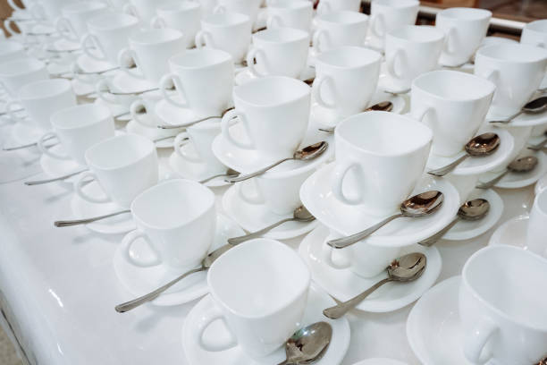 A beautifully arranged table is adorned with elegant white cups that come complete with matching saucers and delicate spoons, perfectly prepared to serve warm beverages to cherished guests