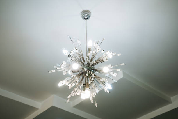 A stunning and beautifully designed chandelier gracefully hangs from the ceiling, adding an exquisite charm and a warm ambiance to the entire room, enhancing its overall aesthetic appeal