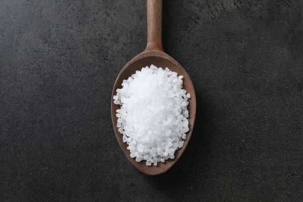 istock Natural salt in wooden spoon on dark grey table, top view 2204268624