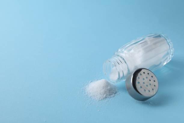 istock Organic white salt in shaker on light blue background, closeup. Space for text 2204268656