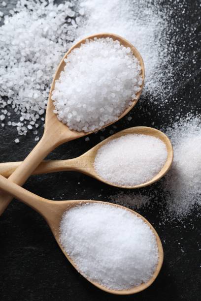 istock Organic salt in spoons on black table, flat lay 2204268736