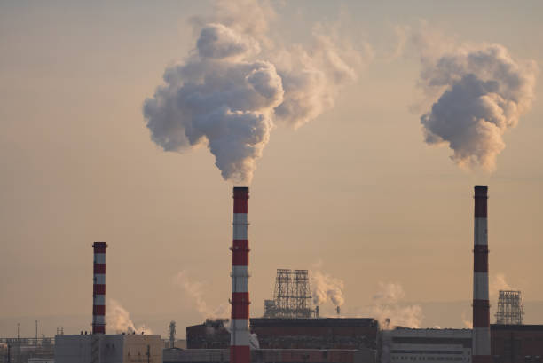 istock Industrial smokestacks emitting white plumes against hazy sunset sky, silhouetting environmental impact of manufacturing pollution at twilight 2204268926