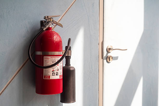istock Fire Extinguisher Mounted on Wall Near Door in Bright Interior 2204270222