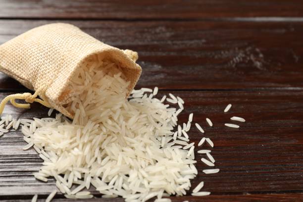 istock Raw basmati rice and bag on wooden table, space for text 2204270503