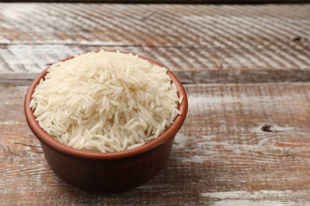 istock Raw basmati rice in bowl on wooden table, space for text 2204270518