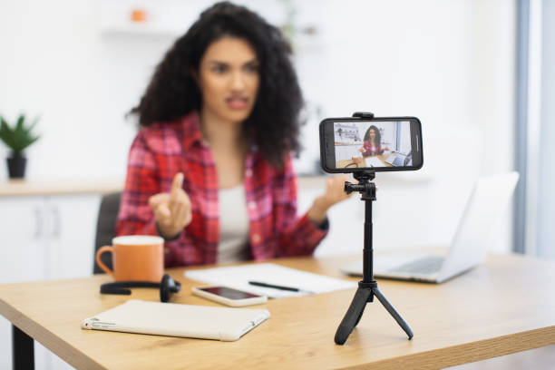 istock Young woman recording video with smartphone while sitting at desk 2204271278