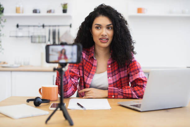 istock Woman recording video blog using smartphone in modern kitchen setting 2204271283